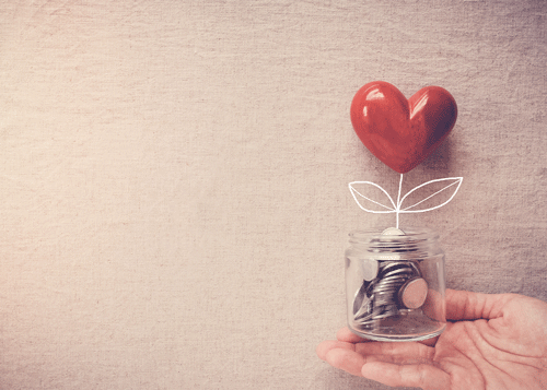 Photo of a hand holding a jar with coins with a heart growing from it, symbolizing a flower. 